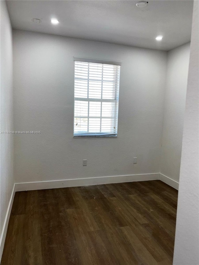 unfurnished room featuring dark wood-style flooring, baseboards, and recessed lighting