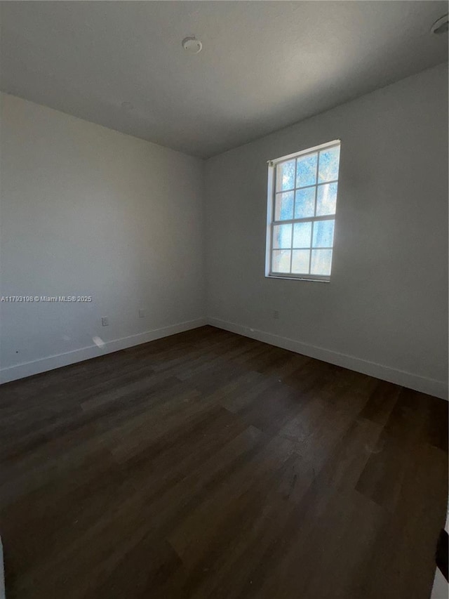 empty room with baseboards and dark wood finished floors