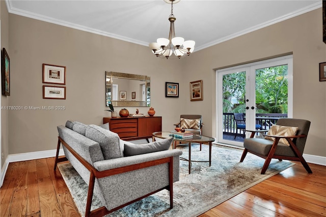 living area featuring an inviting chandelier, baseboards, ornamental molding, and wood-type flooring