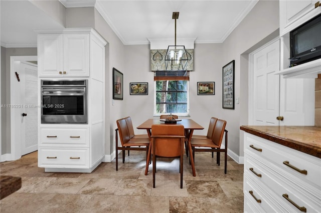 dining area with crown molding, baseboards, stone finish floor, and a notable chandelier