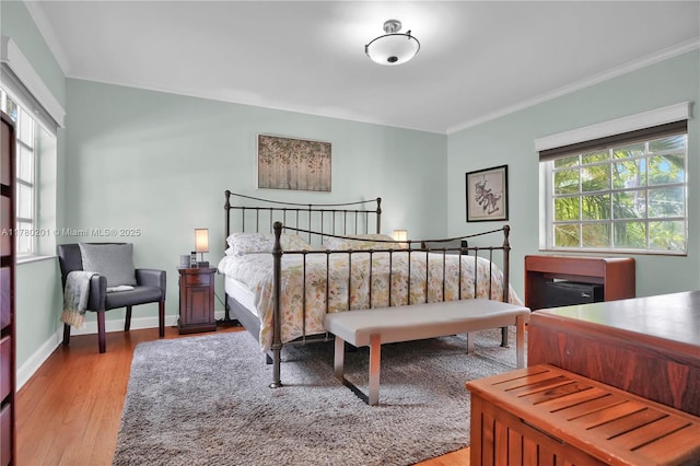 bedroom with crown molding, baseboards, and light wood-style flooring