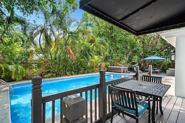 outdoor pool with outdoor dining area, a fenced backyard, and a deck