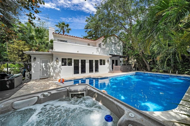 pool featuring an outdoor hot tub, french doors, and a patio area