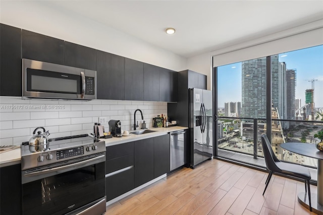 398 NE 5th St Unit 1805, Miami, FL 33132 - kitchen with decorative backsplash, floor to ceiling windows, dark cabinetry, a sink, and appliances with stainless steel finishes