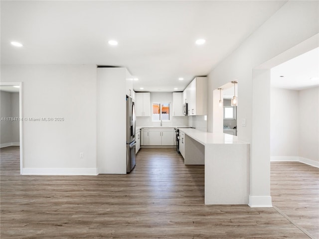 5397 W 14th Ct, Hialeah, FL 33012 - kitchen featuring a sink, light countertops, stainless steel appliances, white cabinetry, and light wood-type flooring