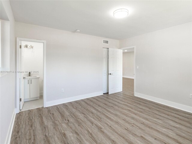 5397 W 14th Ct, Hialeah, FL 33012 - unfurnished bedroom featuring visible vents, a sink, baseboards, light wood-style floors, and ensuite bath