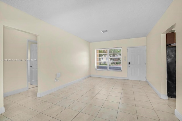 empty room with light tile patterned floors, baseboards, and visible vents