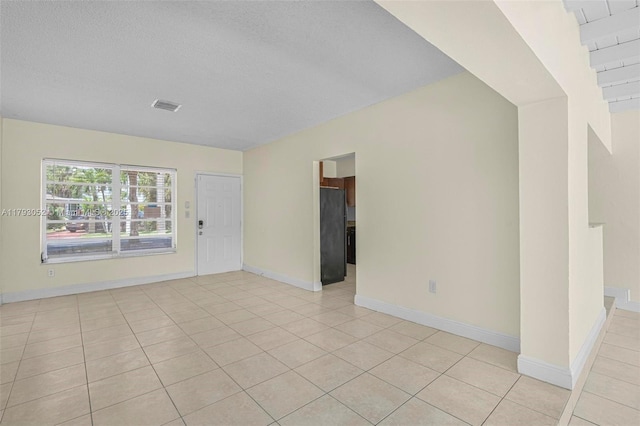unfurnished room featuring visible vents, a textured ceiling, baseboards, and light tile patterned floors