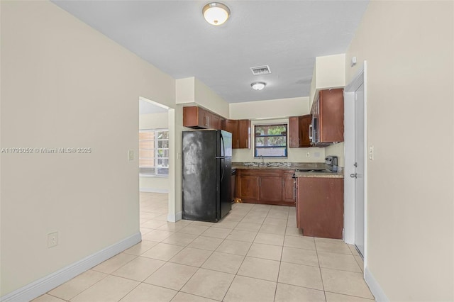 kitchen featuring visible vents, freestanding refrigerator, baseboards, a sink, and light tile patterned floors