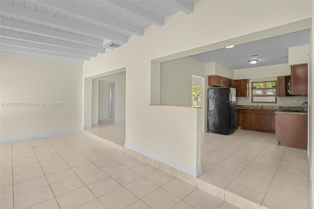 kitchen with freestanding refrigerator, light tile patterned flooring, beamed ceiling, baseboards, and open floor plan
