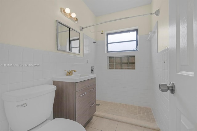 bathroom with vanity, a tile shower, toilet, and tile walls