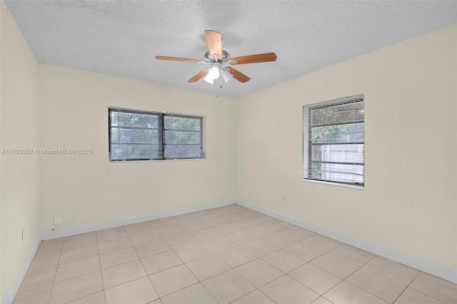 spare room featuring baseboards, a ceiling fan, a textured ceiling, and light tile patterned flooring