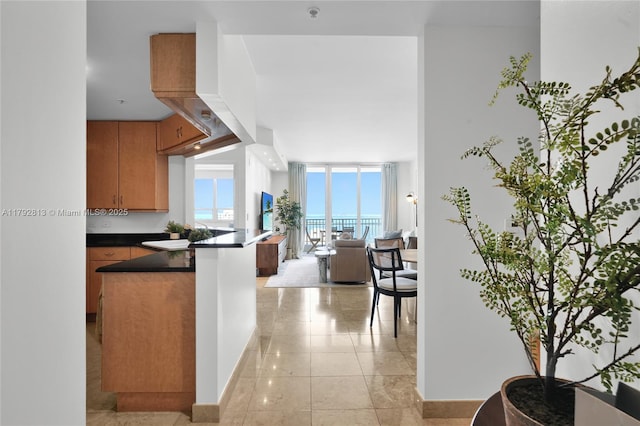801 Brickell Key Blvd Unit 3105, Miami, FL 33131 - kitchen featuring brown cabinetry, a peninsula, dark countertops, baseboards, and open floor plan