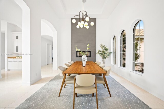 4991 E Sterling Ranch Cir, Davie, FL 33314 - dining area with light tile patterned floors, a chandelier, a tray ceiling, arched walkways, and a high ceiling