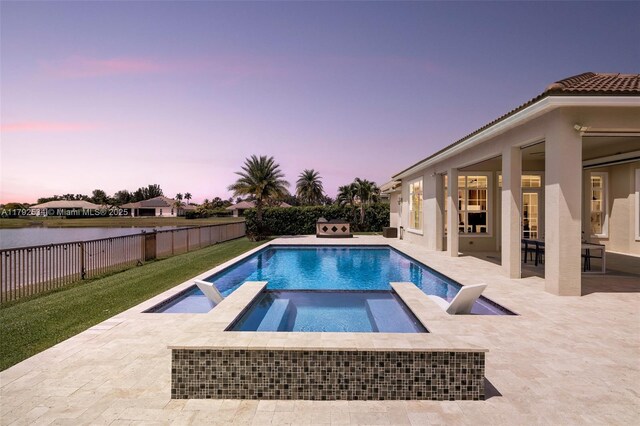 4991 E Sterling Ranch Cir, Davie, FL 33314 - pool at dusk featuring a patio area, a fenced backyard, and a pool with connected hot tub