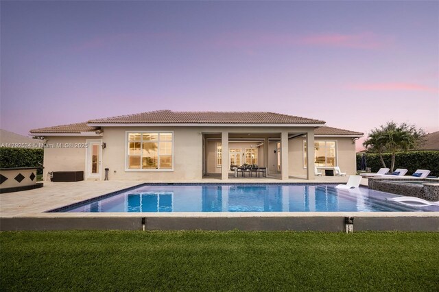 4991 E Sterling Ranch Cir, Davie, FL 33314 - back of property at dusk with stucco siding, a tile roof, an outdoor hot tub, and a patio