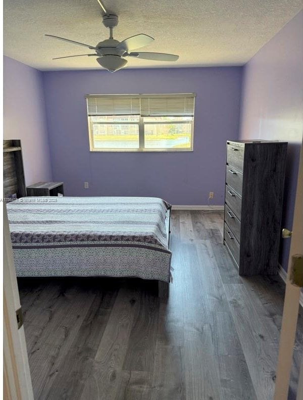 bedroom featuring baseboards, a ceiling fan, a textured ceiling, and wood finished floors