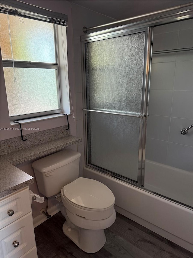 bathroom featuring vanity, combined bath / shower with glass door, wood finished floors, and toilet