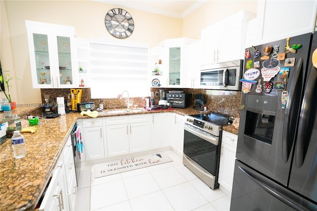 kitchen featuring crown molding, decorative backsplash, white cabinets, a sink, and appliances with stainless steel finishes