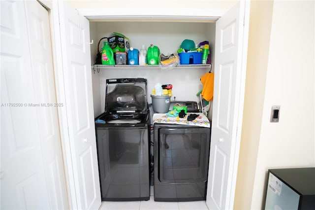 clothes washing area with tile patterned floors, laundry area, and washer and dryer