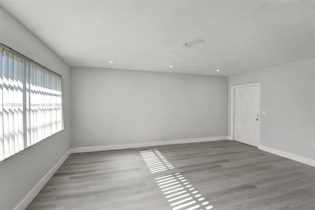 empty room with baseboards, recessed lighting, and wood finished floors