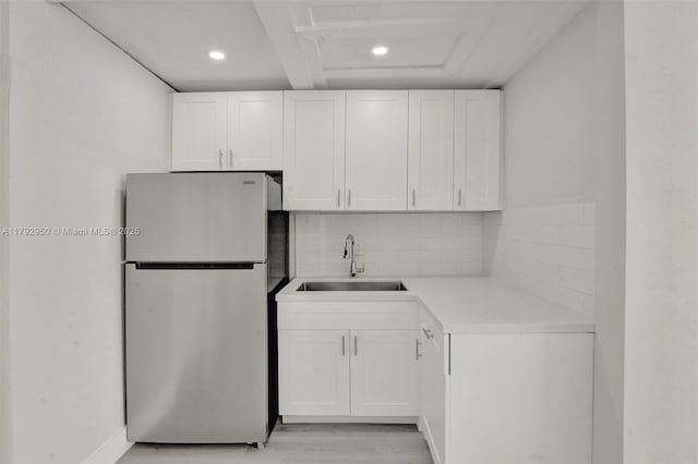 kitchen featuring a sink, freestanding refrigerator, recessed lighting, and white cabinetry