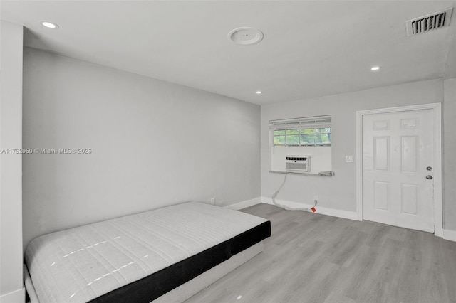 unfurnished bedroom featuring cooling unit, recessed lighting, baseboards, wood finished floors, and visible vents