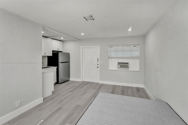interior space with visible vents, light wood-type flooring, baseboards, cooling unit, and recessed lighting