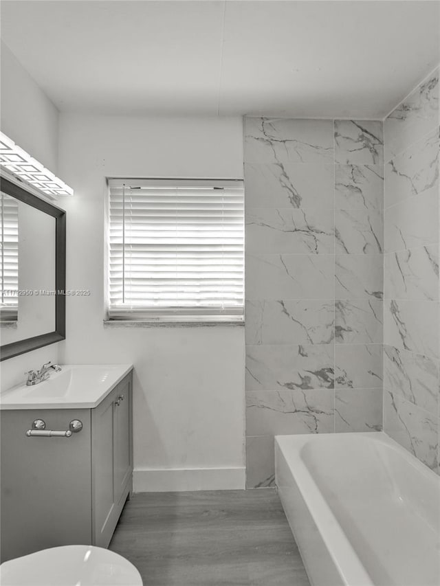 bathroom featuring toilet, baseboards, wood finished floors, and vanity
