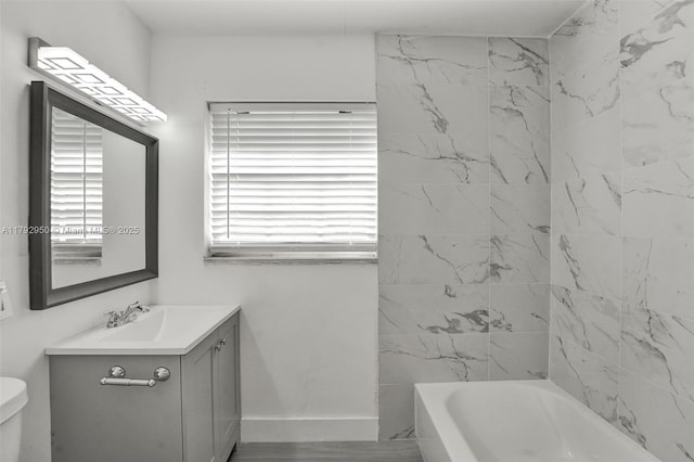 full bath featuring vanity, baseboards, washtub / shower combination, and toilet