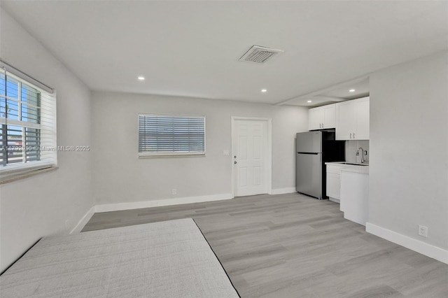 interior space featuring recessed lighting, freestanding refrigerator, white cabinetry, and light wood-style floors