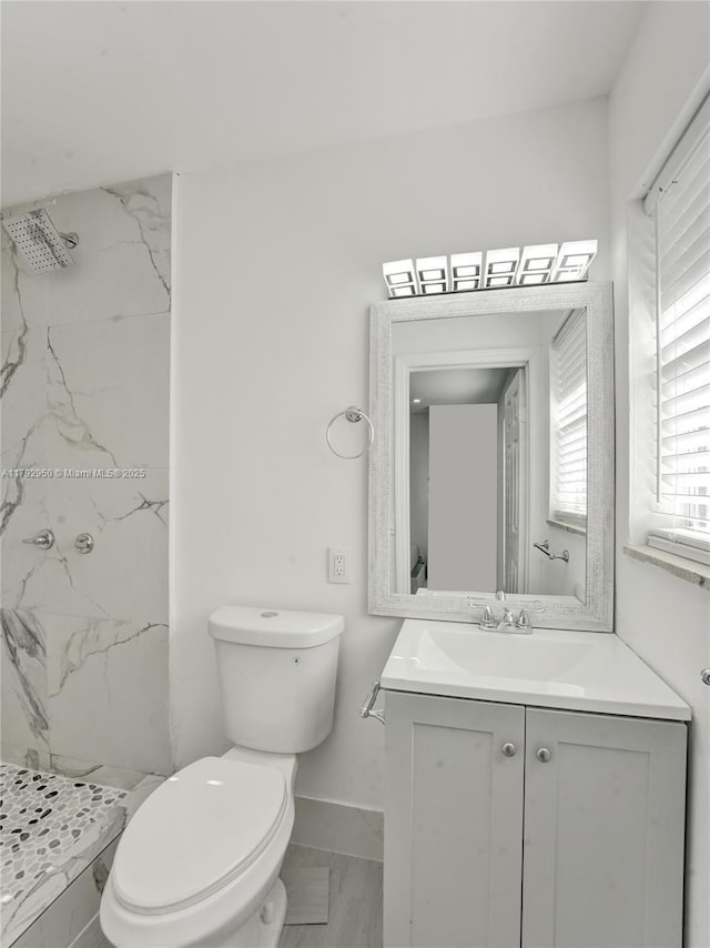bathroom featuring a marble finish shower, baseboards, vanity, and toilet