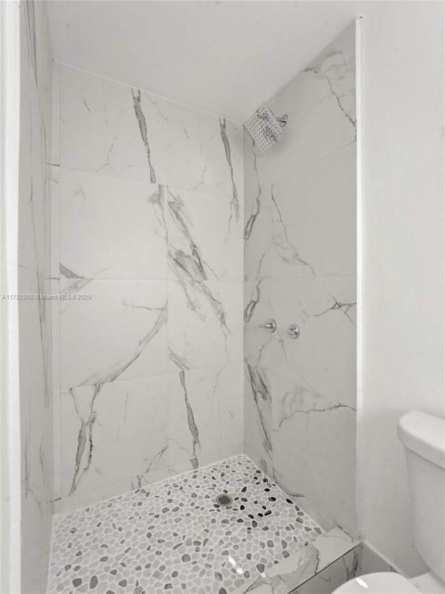 bathroom with toilet and a marble finish shower