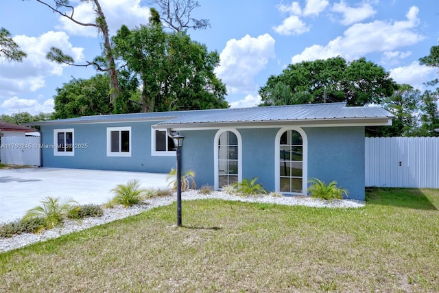 ranch-style house featuring fence, metal roof, a front yard, and stucco siding
