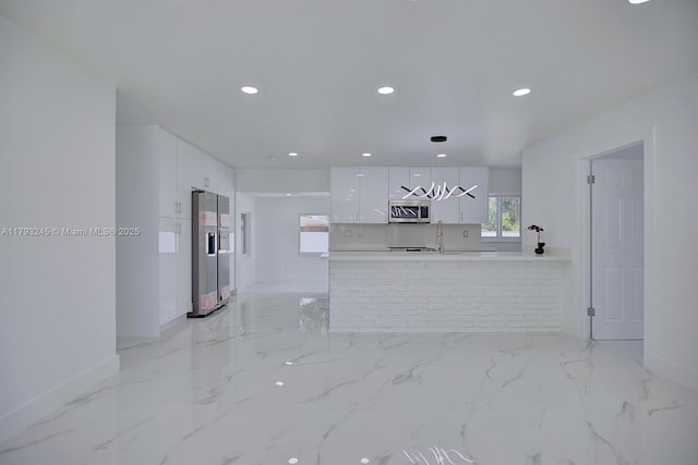unfurnished living room with baseboards, recessed lighting, and marble finish floor