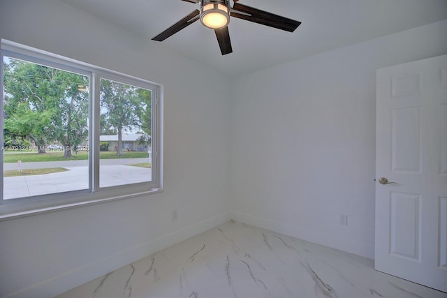 unfurnished room with a ceiling fan, baseboards, and marble finish floor