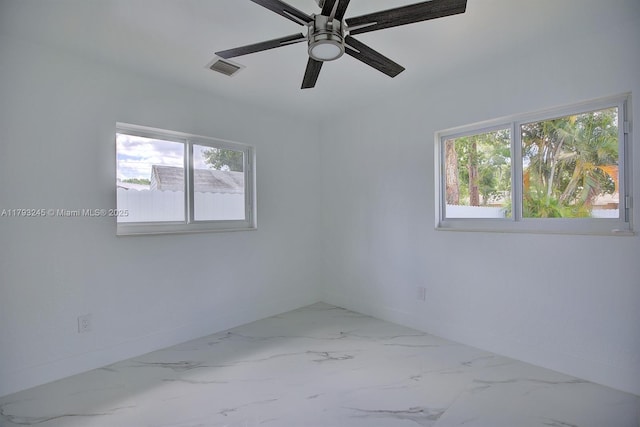 spare room with baseboards, marble finish floor, and a wealth of natural light