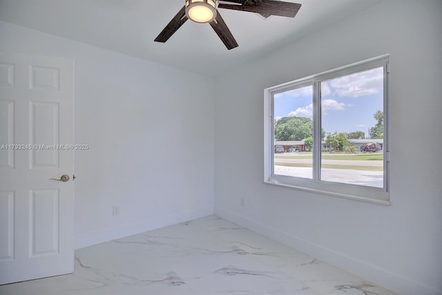 empty room with baseboards, ceiling fan, and marble finish floor