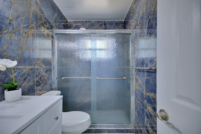full bathroom featuring vanity, tile walls, a shower stall, and toilet