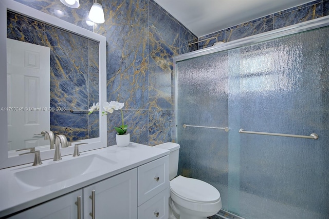full bathroom with vanity, tile walls, toilet, and a shower stall