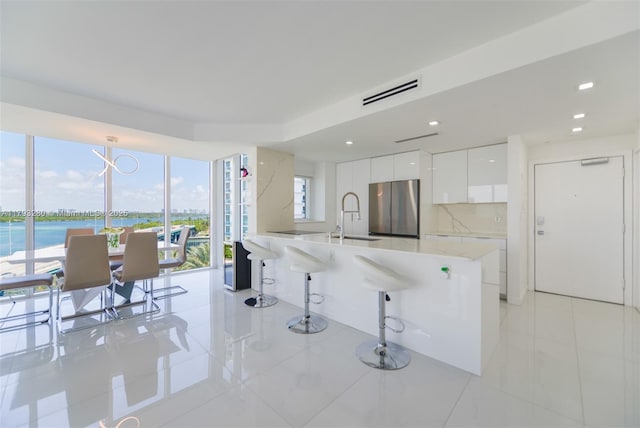 10275 Collins Ave Unit 731, Bal Harbour, FL 33154 - kitchen featuring freestanding refrigerator, modern cabinets, a sink, white cabinetry, and a breakfast bar area