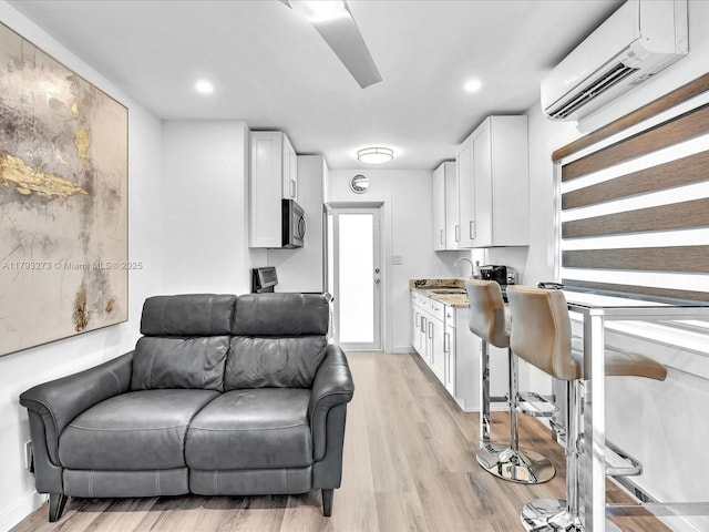 interior space featuring recessed lighting, baseboards, a wall mounted AC, and light wood finished floors