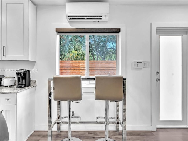 dining room with baseboards, a wall mounted AC, and wood finished floors