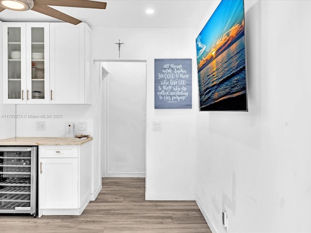 bar featuring beverage cooler, indoor bar, light wood-type flooring, recessed lighting, and a ceiling fan
