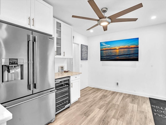 kitchen with high end refrigerator, light wood-style flooring, white cabinetry, and wine cooler
