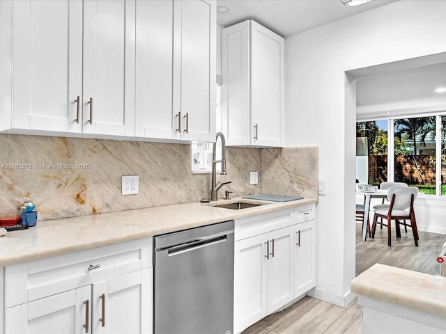 kitchen featuring a sink, dishwasher, light wood-style flooring, white cabinetry, and decorative backsplash