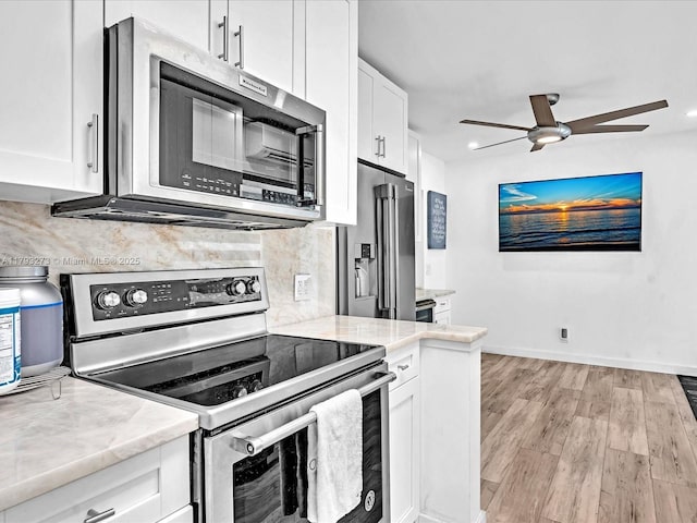 kitchen featuring light wood-style floors, stainless steel appliances, a ceiling fan, white cabinetry, and tasteful backsplash