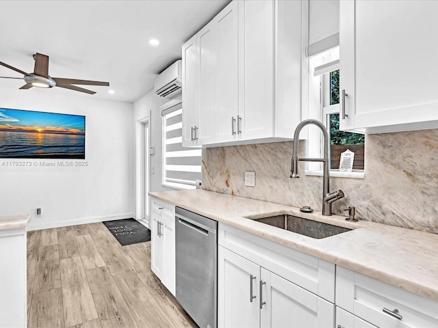 kitchen featuring a sink, stainless steel dishwasher, a wall mounted air conditioner, and white cabinetry