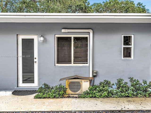 doorway to property featuring ac unit and stucco siding