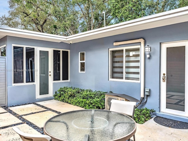 property entrance featuring a patio, stucco siding, and outdoor dining space